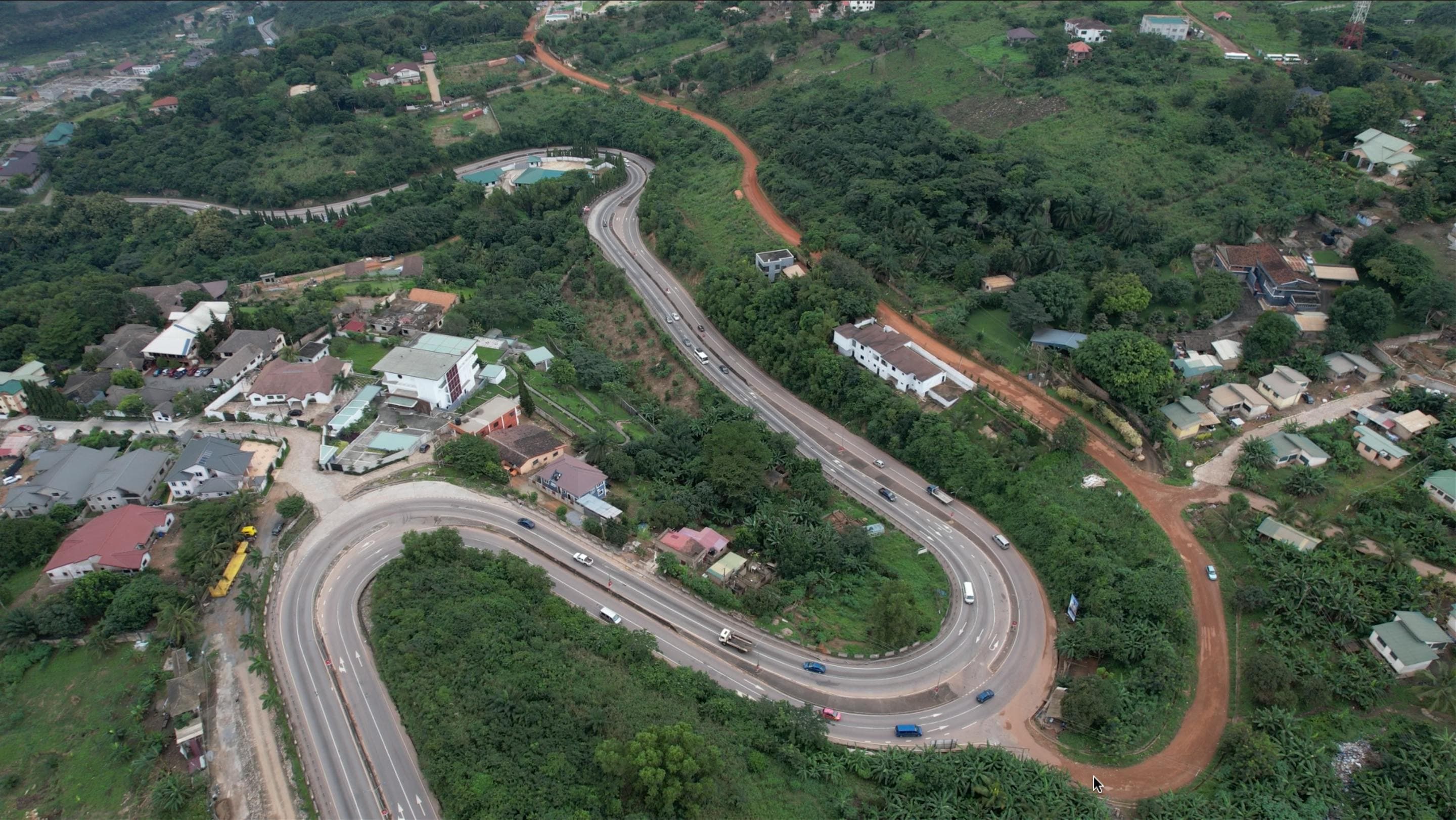 Aerial view of Aburi, Ghana - showcasing lush green forests, winding roads, and peaceful community nestled in the hills